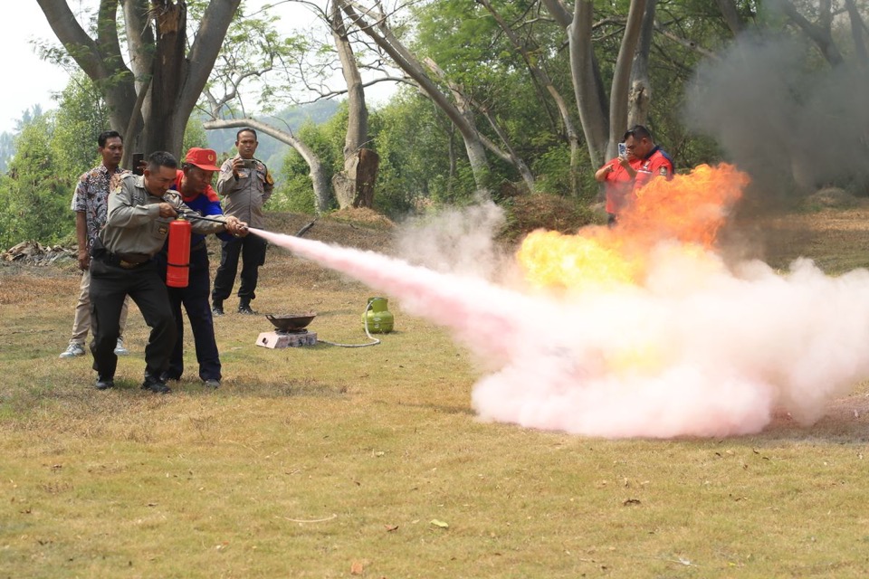 Learners practising with a fire extinguisher on a training ground