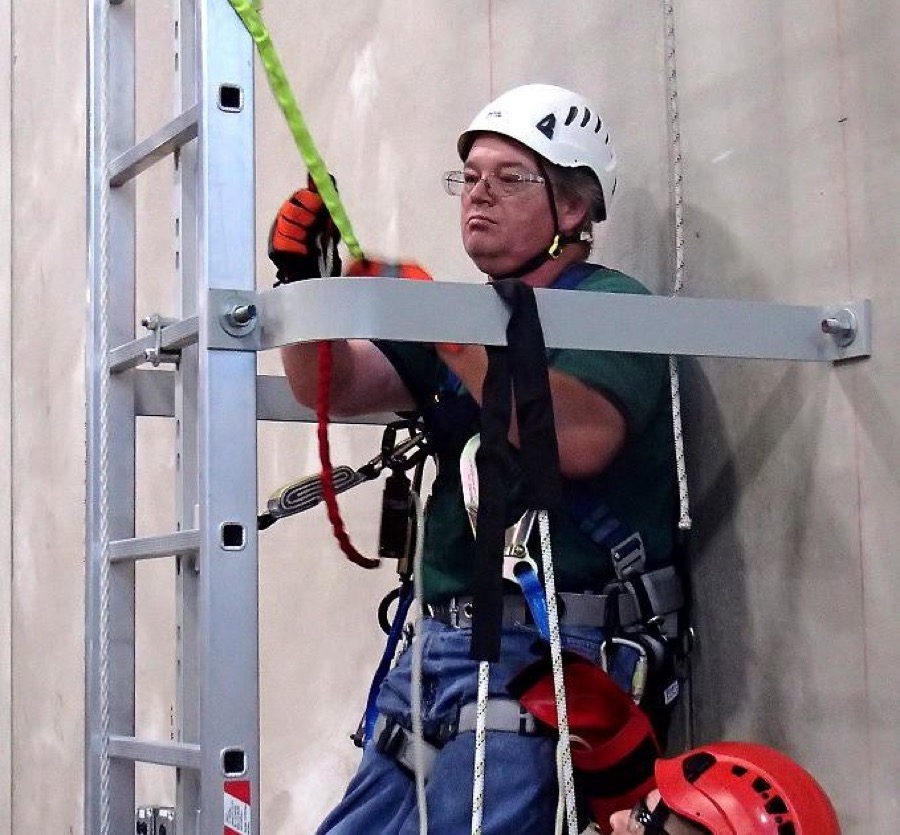 A safety instructor guiding a trainee through rope rescue equipment during hands-on training